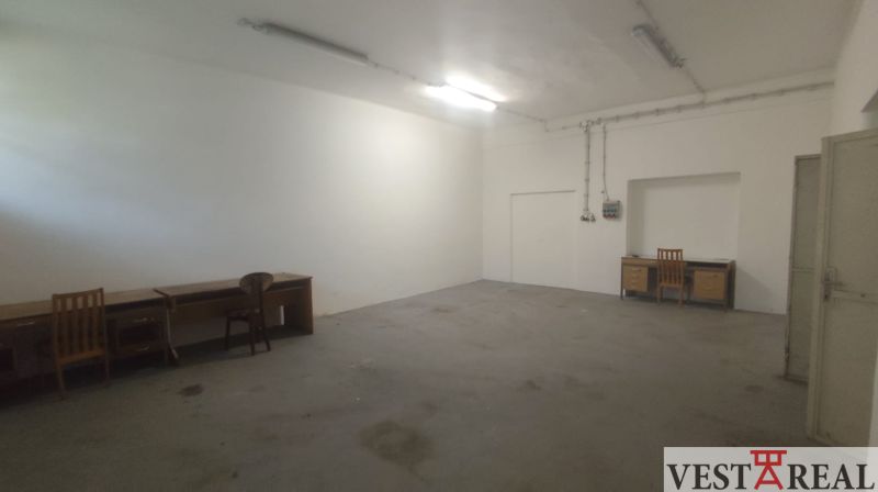 Empty room with tables and chairs in warehouse and hall spaces.