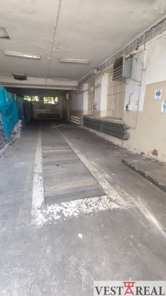 Interior of an industrial space with a gray floor and piping, suitable for warehouses and halls.