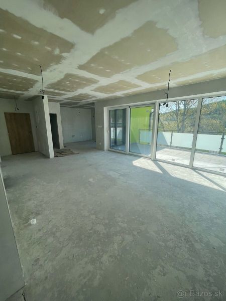 Living room in a three-room apartment with large windows and a concrete floor.