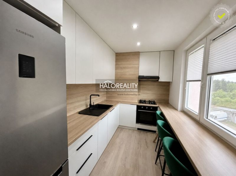 A kitchen in a 2-room apartment with a wooden decor floor and modern equipment.