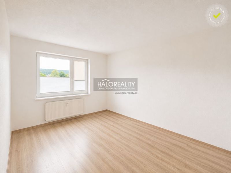 A bright room with a large window and a wooden decor floor in a two-room apartment.