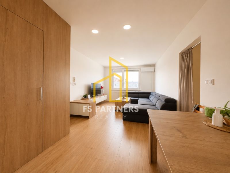 Living room in a three-room apartment with a wooden decor floor and a spacious sofa.