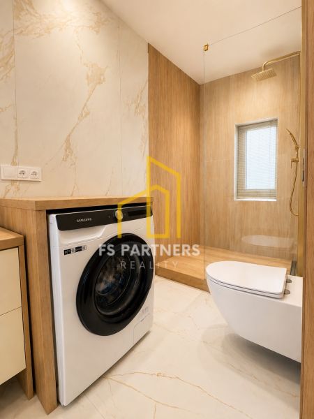 Bathroom in a 3-room apartment with a washing machine, shower cabin, and toilet, floor with wooden decor.