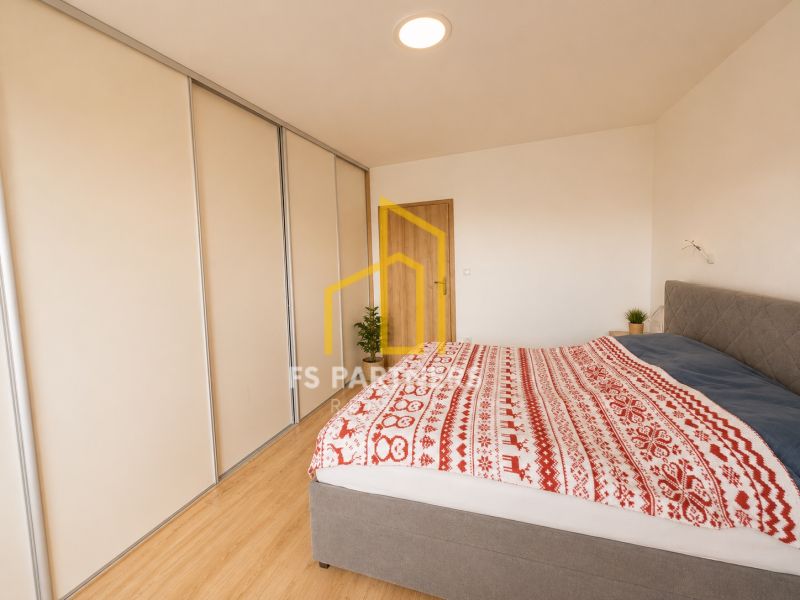 Bedroom with wood-patterned flooring in a 3-room apartment with a built-in wardrobe.