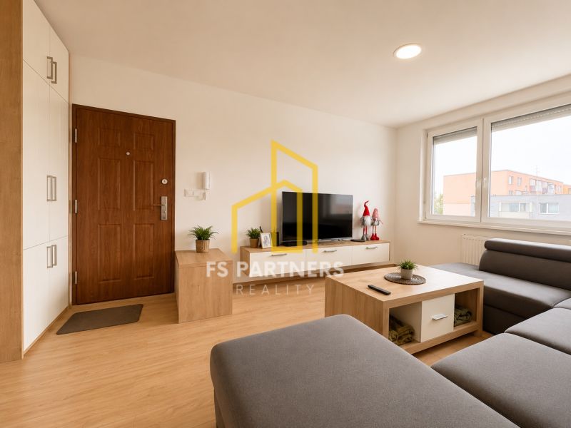 Living room of a three-room apartment with a wooden decor floor, gray sofa, and television.
