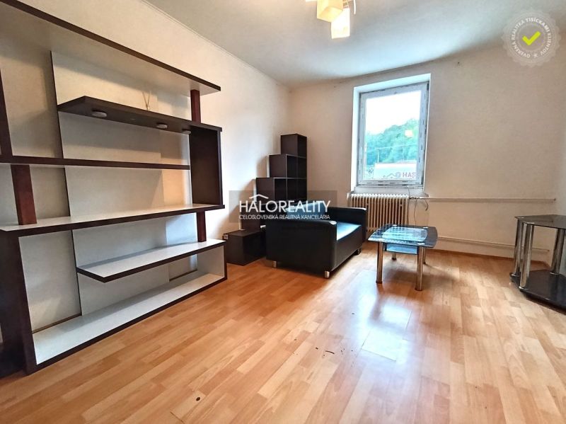 Living room in a 3-room apartment with a sofa, shelves, and a wooden decor floor.