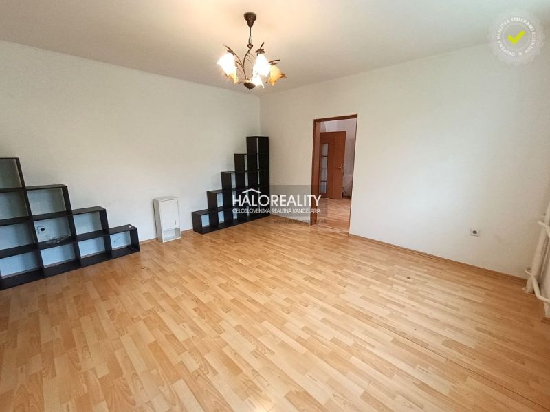A room in a 3-room apartment with a wooden decor floor and shelves.