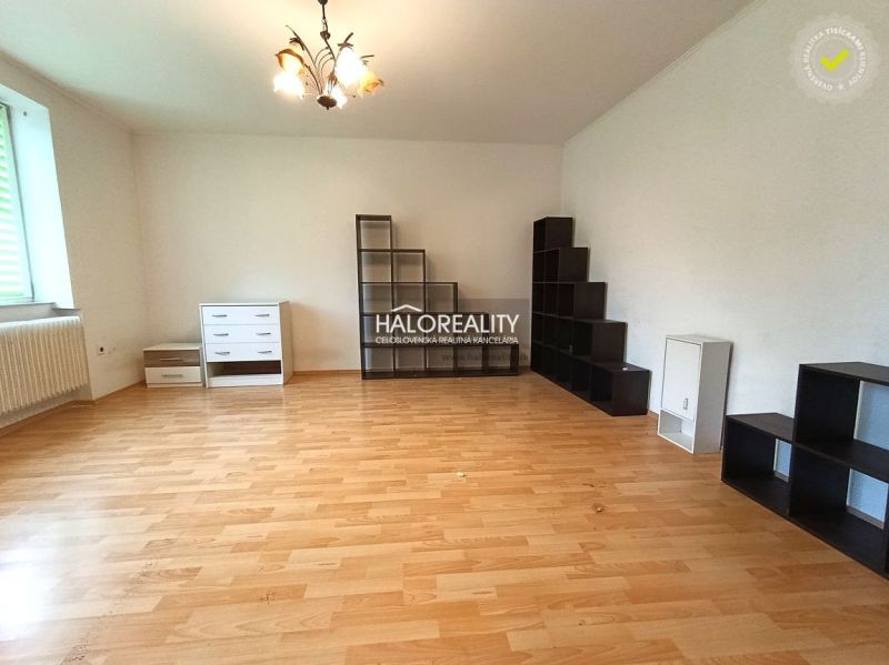 Living room with a shelving system, sofa, and wooden decor flooring in a 3-room apartment.