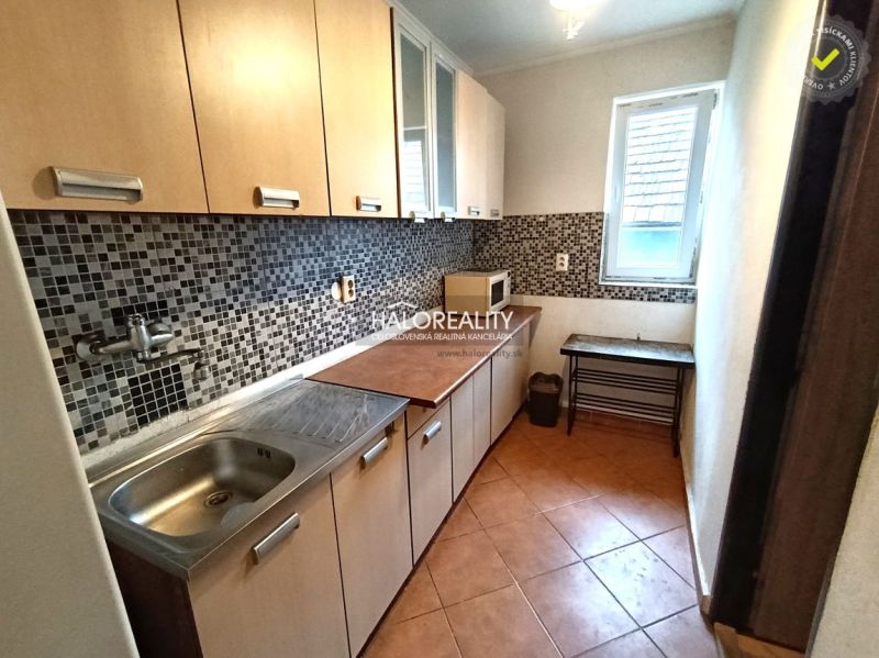 A kitchen of a three-room apartment with mosaic tiles and a wooden decor floor.