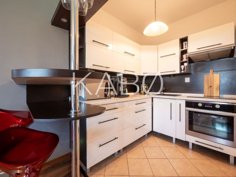 A kitchen with white cabinets in a two-room apartment and a floor with a wood decor.