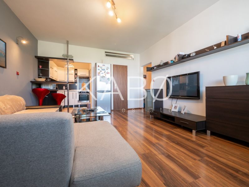Living room in a two-room apartment with a wooden decor floor and a comfortable sofa.