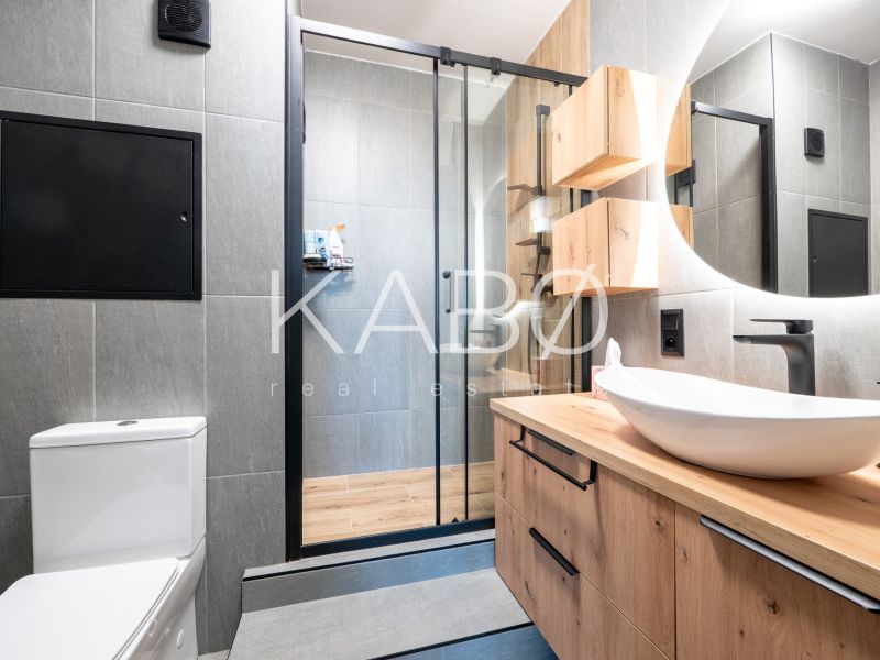 Bathroom in a 2-room apartment with wood-patterned flooring and a shower corner.
