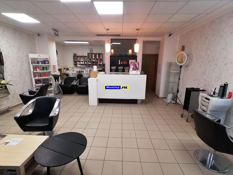 Interior of commercial premises with hairdressing equipment, sofas, and shelves with products.
