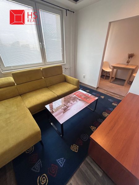 Living room in a three-room apartment with a wooden decor floor and a yellow sofa.