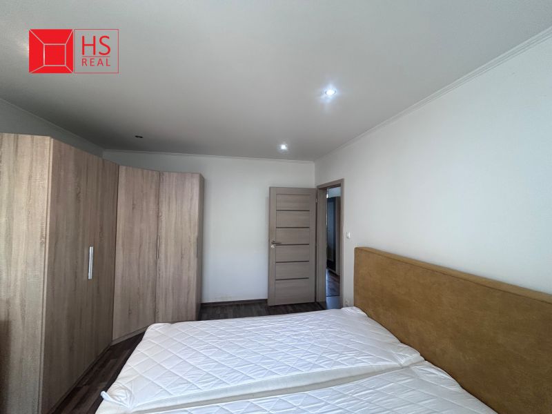 Bedroom with a double bed, built-in wardrobe, and wooden decor flooring in a 3-room apartment.