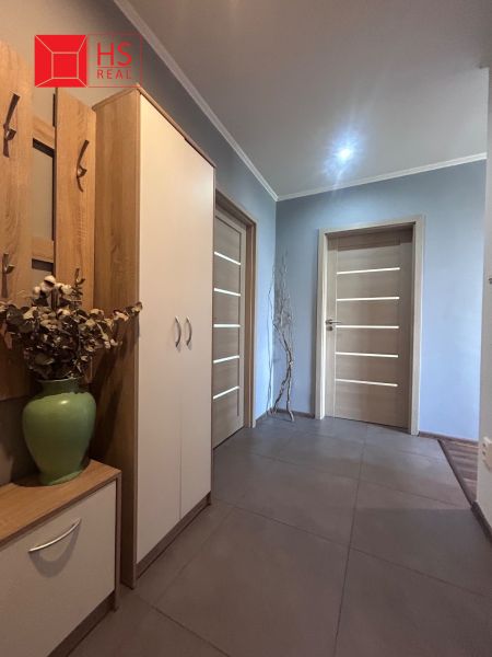 A hallway in a 3-room apartment with a decorative vase and wooden doors.
