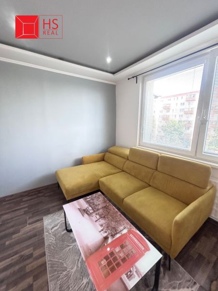 Living room with a mustard sofa, coffee table, and wooden decor flooring.