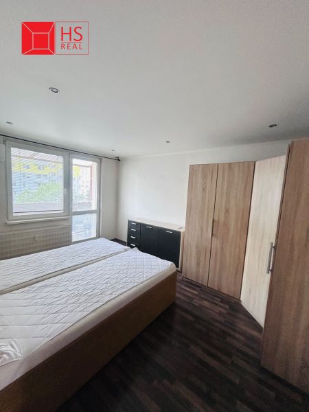 A bedroom in a three-room apartment with a wooden decor floor and furniture.