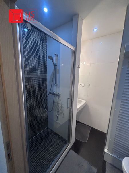 A bathroom in a three-room apartment with a shower and white tiles.
