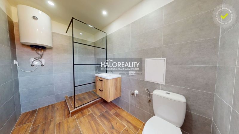 A bathroom in a 2-room apartment with a wooden decor floor and a shower corner.