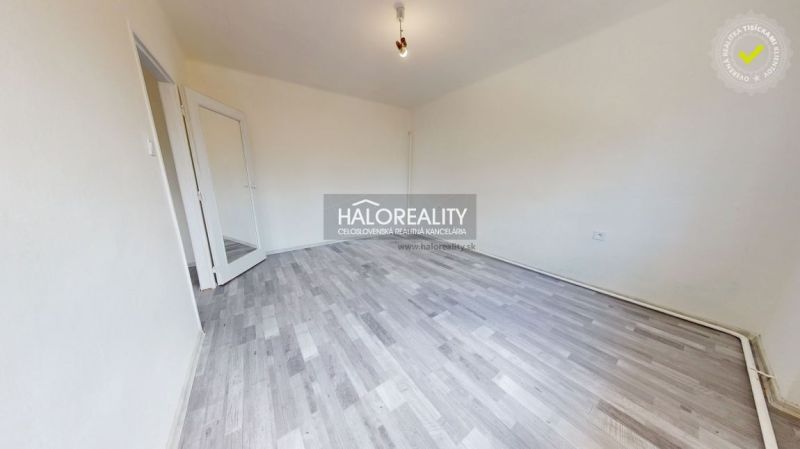 An empty room with white walls and a wooden-patterned floor, doors with glass.