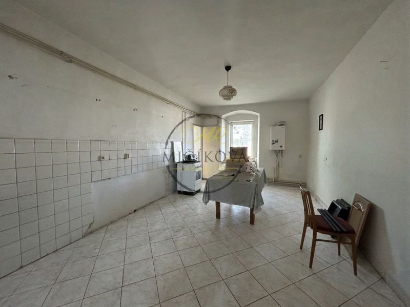 White kitchen in a family house with simple furnishings and tiled floor.