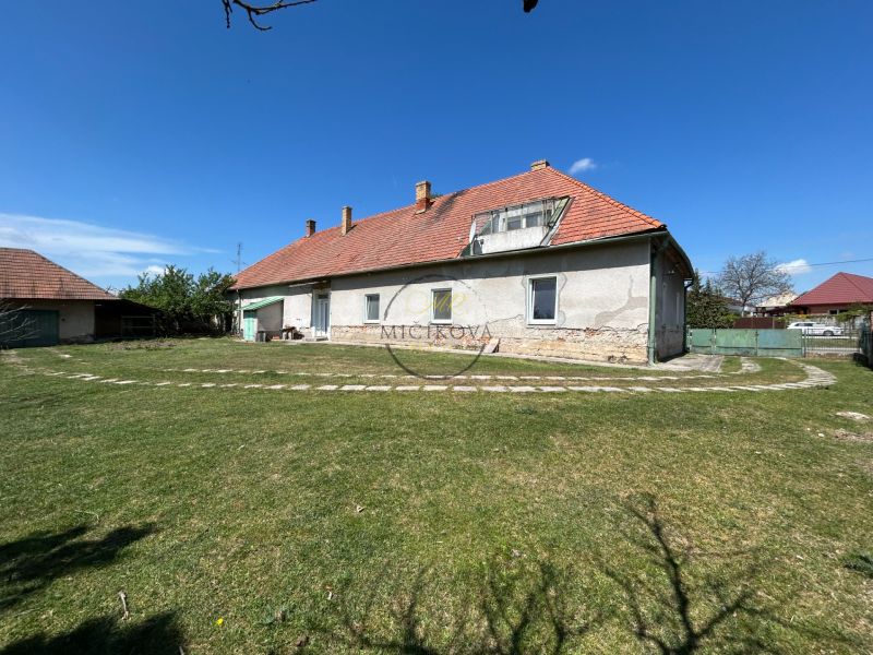 A family house in Čifáre with a large garden and a brick roof under a blue sky.