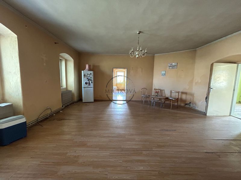 Interior of a family house with a wooden decor floor, older furniture, and a refrigerator.