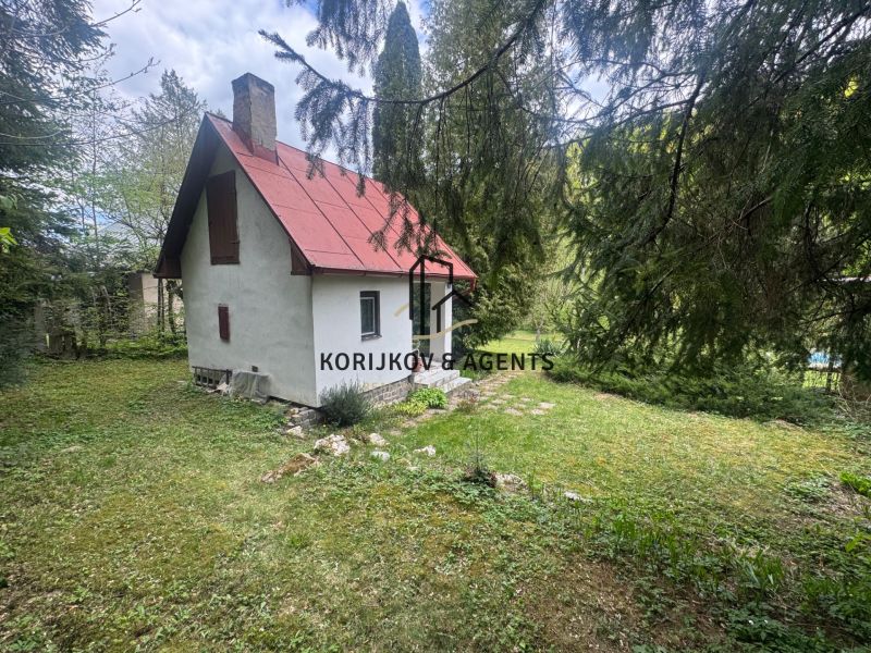 A garden cottage in Svinica surrounded by trees and a grassy plot.