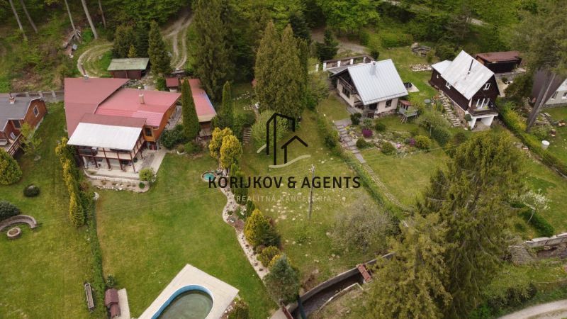 An aerial view of cottages in Nižný Klátov with surrounding greenery and a swimming pool.