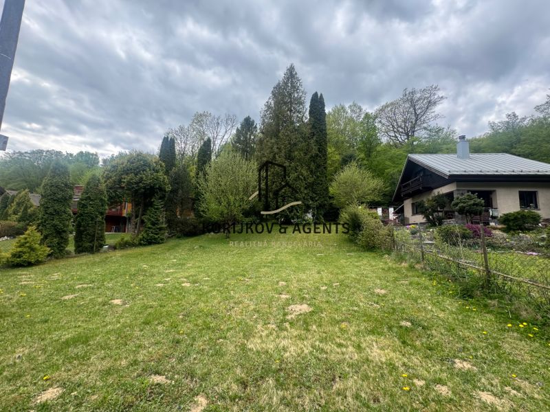 A garden with a cottage in Svinica, surrounded by trees and landscaped greenery.