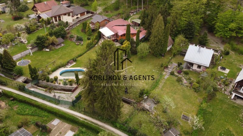 Cottages with gardens and a swimming pool in Nižný Klátov surrounded by greenery and trees.