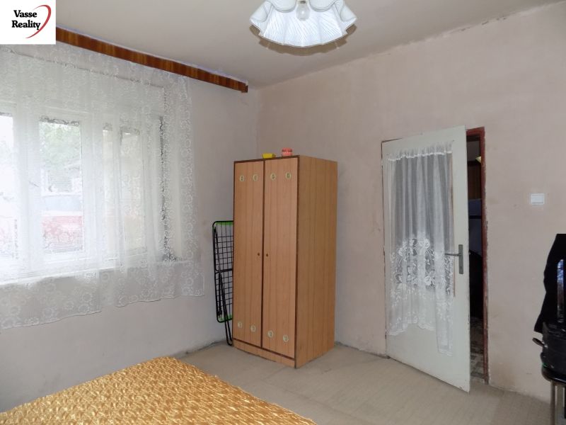 A room with simple furniture, curtains on the window, and a carpet on the floor in a family house.