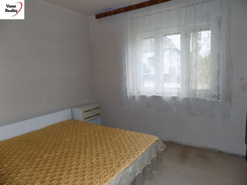 A bedroom in a family house with simple furnishings and curtains on the window.