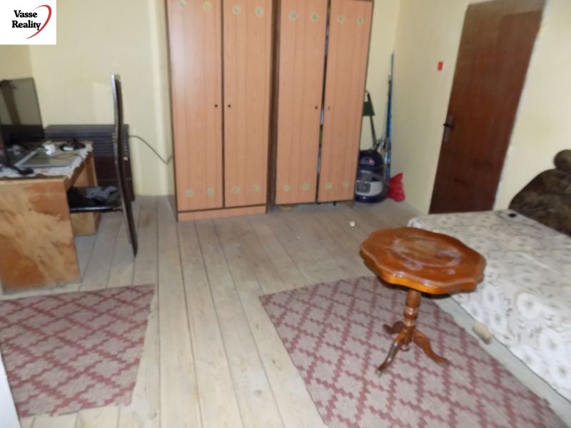 A room in a family house with wooden decor, carpet, furniture, and a table.