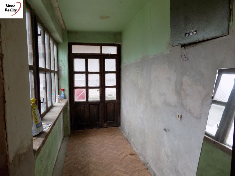 A hallway in a family house with large windows, a floor with a wooden decor.