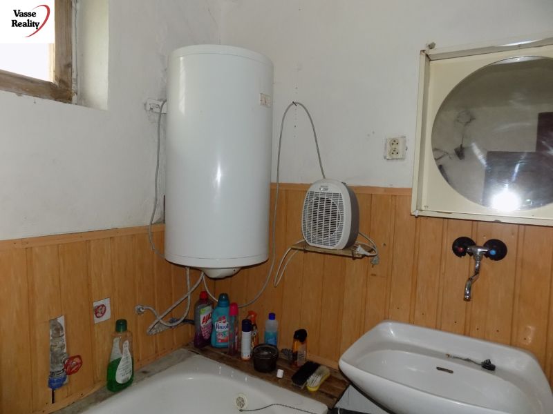 A bathroom in a family house with an electric boiler and a sink.