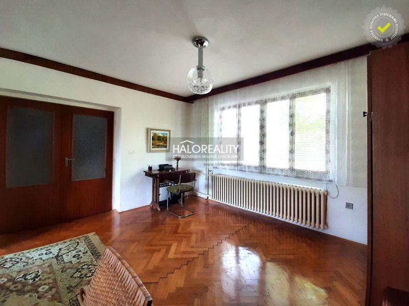 Living room in a family house with wood-patterned flooring and a large window.
