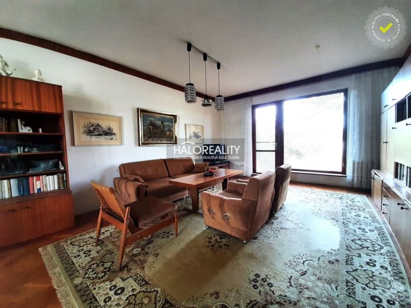 Living room in a family house with carpets, a sofa, and wooden decor.