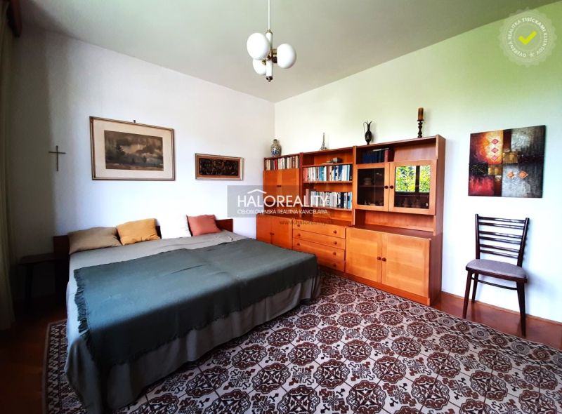 In the family house, there is a room with a bed, a wooden wardrobe, and a carpet.