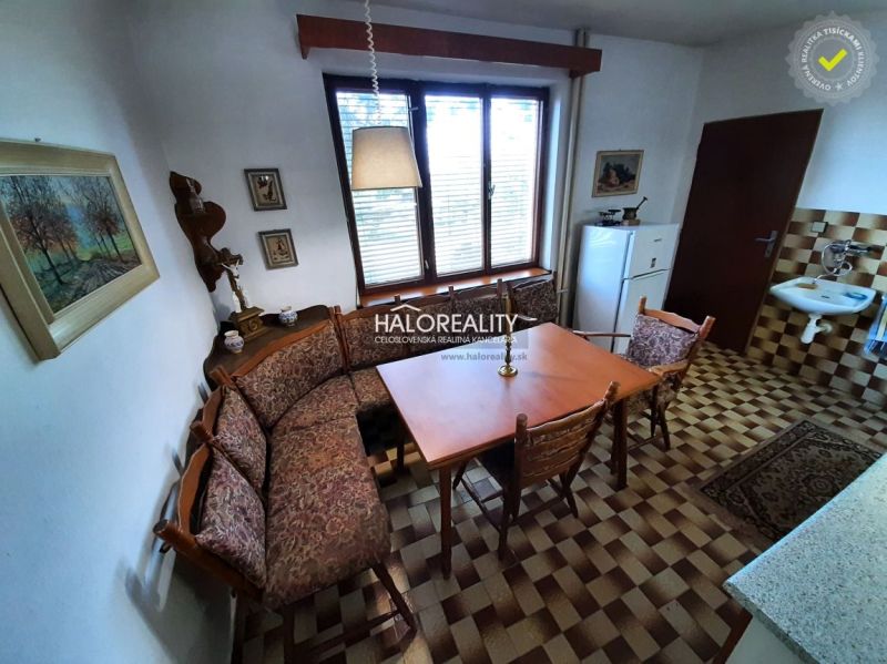 The kitchen in the family house has wooden furniture and a tiled floor.