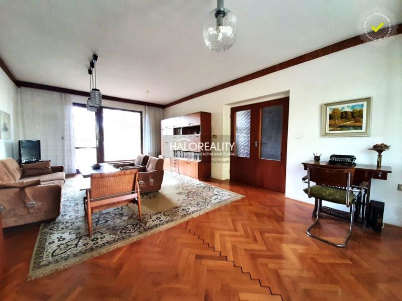 Living room of a family house with a wooden decor floor, comfortable seating, and a writing desk.