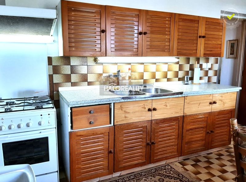 A kitchen in a family house with wooden cabinets and a stove, floor with wooden decor.
