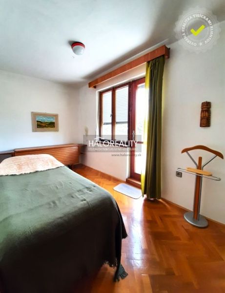 A bedroom in a family house with a bed, a painting, and a wooden decor floor.