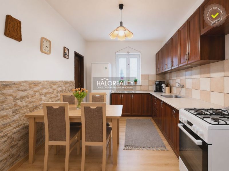 A kitchen in a family house with a wooden decor floor, a dining table, and a kitchen unit.