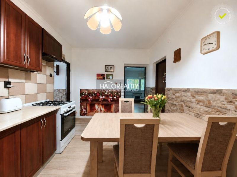 A kitchen in a family house with a kitchen unit, a dining table, and a floor with a wooden decor.