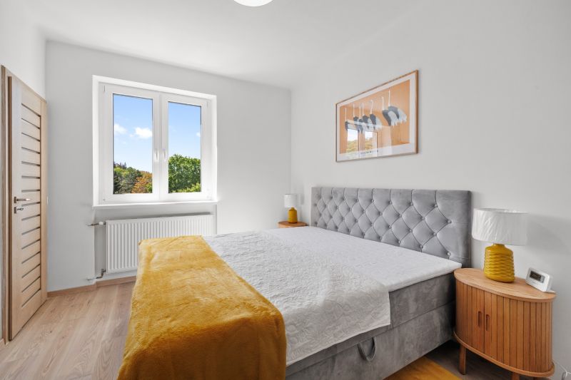 A bright bedroom with wood-patterned flooring, a double bed, and a large window in a 3-room apartment.