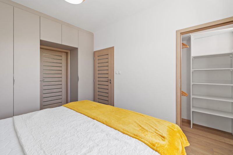 A bedroom in a 3-room apartment with a wooden decor floor and a spacious wardrobe.