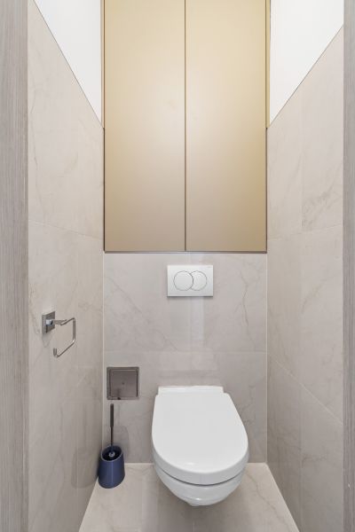 A toilet in a 3-room apartment with neutral-colored tiles and elegant lines.