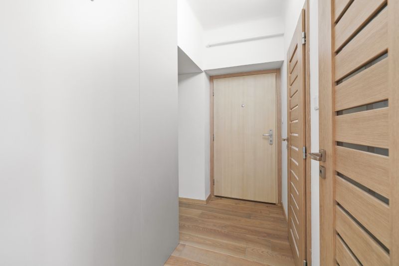 The hallway in a 3-room apartment with a wooden decor floor and doors.